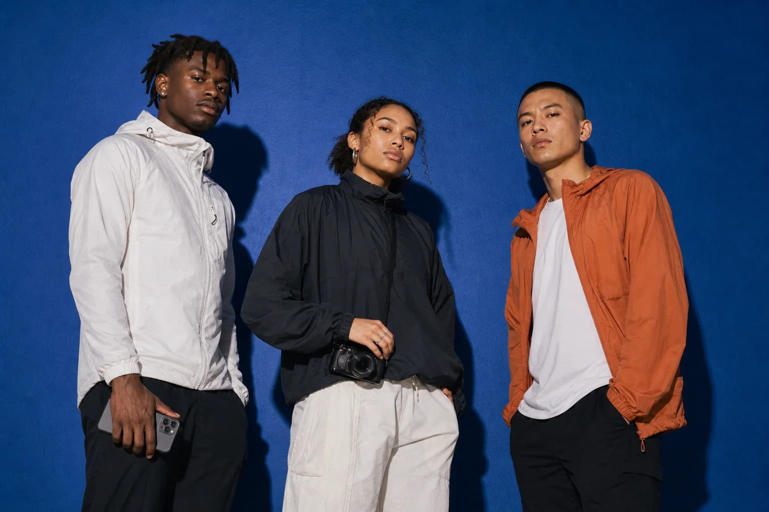 Three athlete-creators posed against a cobalt studio wall