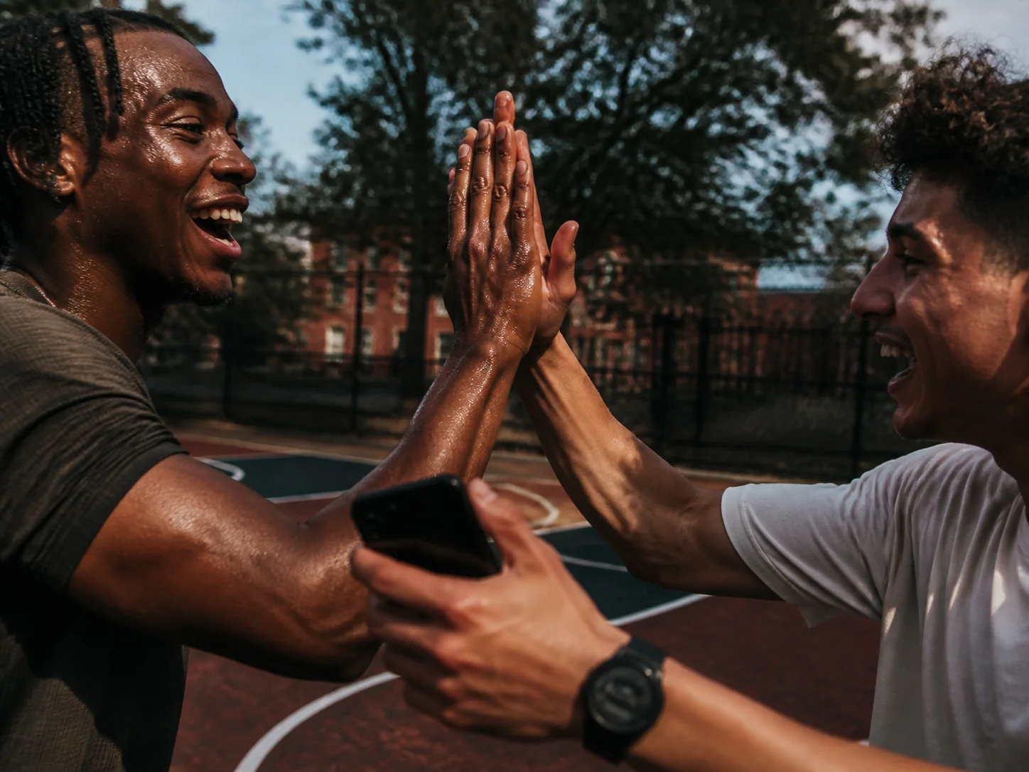 Athletes high-fiving after a street-court game under direct flash