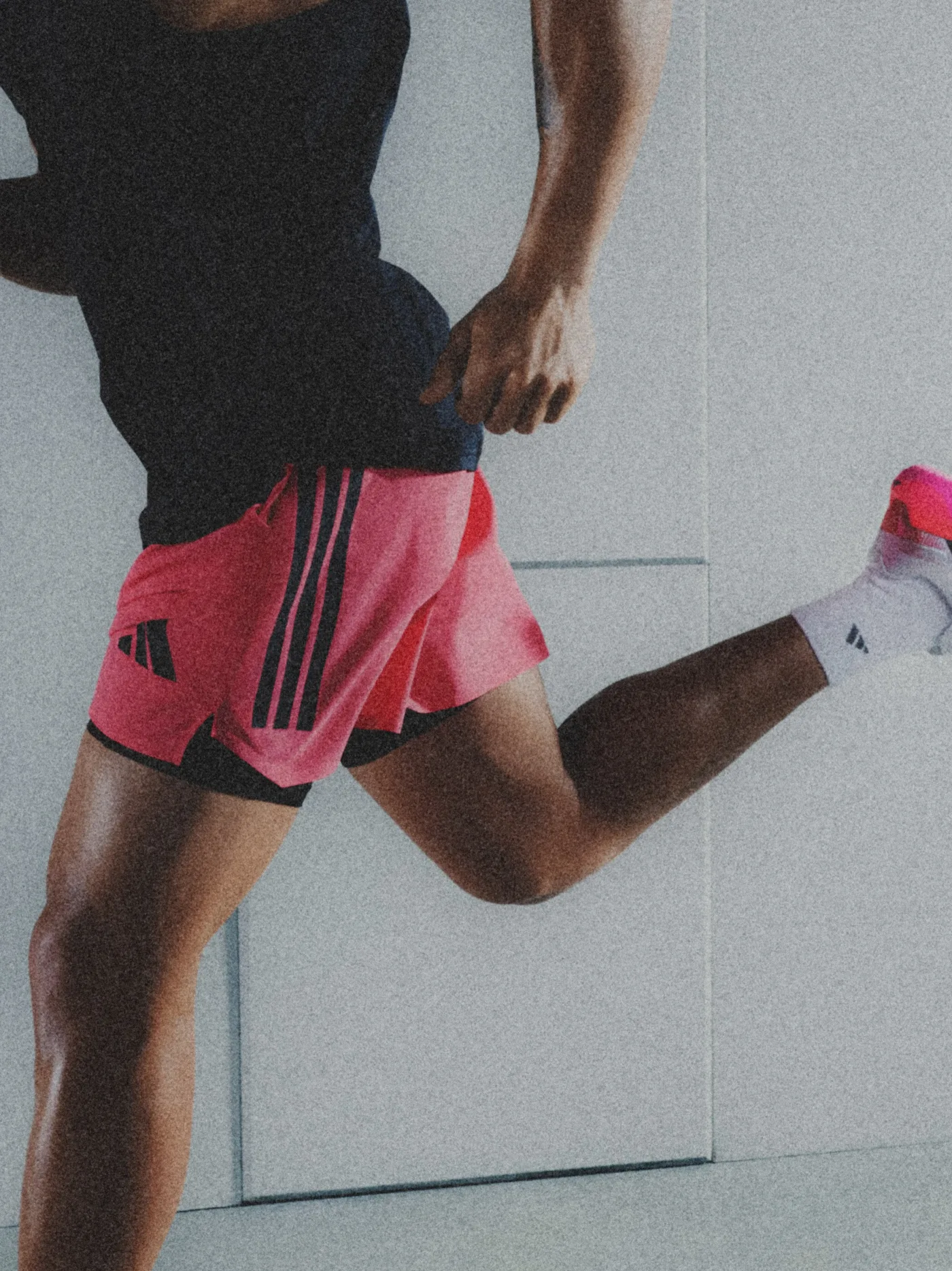 A runner in adidas kit mid-stride against a concrete wall
