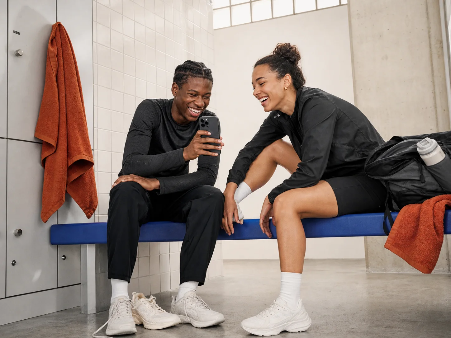 Two runners laughing over a Story captured on a phone after training